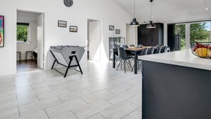 Una cocina moderna con comedor, mesa de fútbol y un ventanal grande.