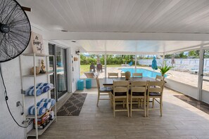 A covered patio with a pool, wooden furniture, and a fan. - Private Pool Getaway • 5min Beach • Sleeps 9 (Jacksonville)