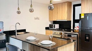 Una cocina moderna con una isla central, electrodomésticos de acero inoxidable y taburetes de bar.