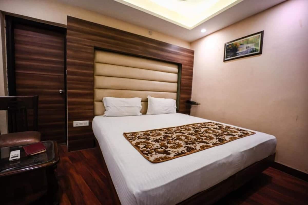 Une chambre à coucher avec un lit, une table de chevet, une chaise et un luminaire au plafond.