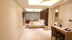 Habitación de hotel moderna con cama, escritorio, silla y ventilador de techo.