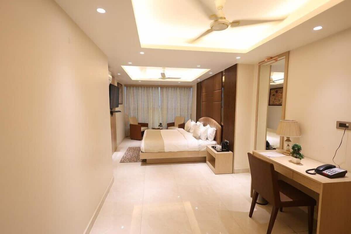 Une chambre d’hôtel moderne équipée d’un lit, d’un bureau, d’une chaise et d’un ventilateur de plafond.