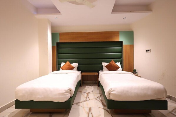 A hotel room with two single beds, a green headboard, and a marble-patterned floor.