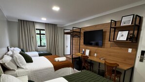 Ein Hotelzimmer mit zwei Betten, einem Schreibtisch, einem Stuhl, einem Fernseher und einem Fenster mit Vorhängen.