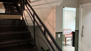 Eine Treppe mit schwarzen Geländern, die zu einer Zwischenebene führt.