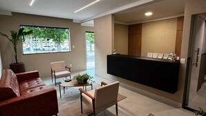 Ein modernes Wohnzimmer mit einer Couch, Sesseln, einem Couchtisch und einem Empfangstresen.