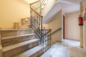 A staircase with marble steps and a wooden handrail, leading to an upper floor. - Room 'Habitación 102' with Balcony, Wi-Fi and Air Conditioning (Granada)