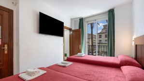 Una habitación de hotel con dos camas, un televisor, un balcón con vistas y una puerta.