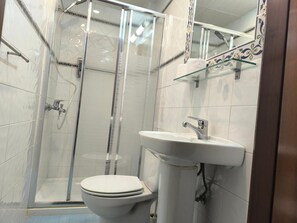 Kylpyhuone, jossa on wc, pesuallas ja lasinen suihkuseinä.