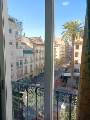 A view from a window overlooking a residential area with multi-story buildings, a palm tree, and a street with parked cars. - Room 'Habitación 308 Triple' with Balcony, Wi-Fi and Air Conditioning (Granada)