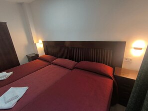 A hotel room with a large bed, two bedside tables, and wall-mounted lights. - Room 'Habitación 308 Triple' with Balcony, Wi-Fi and Air Conditioning (Granada)