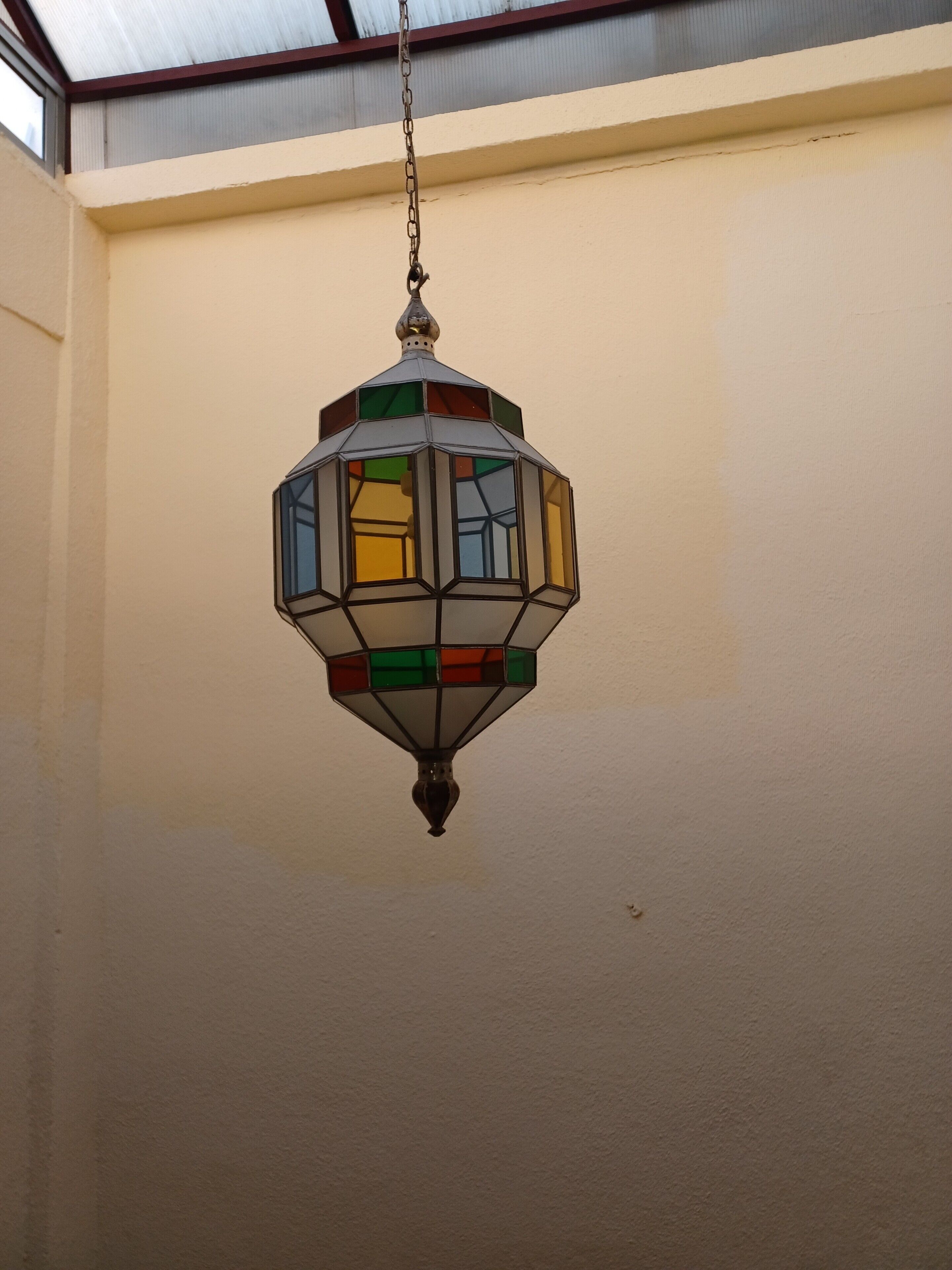 A hexagonal hanging light fixture with a chain.