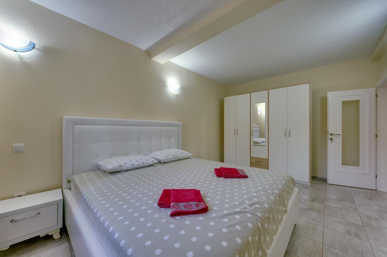 A bedroom with a bed, nightstand, wardrobe, and a door.
