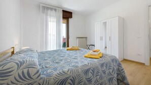 Une chambre à coucher avec un lit, une armoire, un radiateur et une fenêtre avec des rideaux.