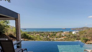 Una piscina infinita privada con vistas al mar y a un pueblo en la ladera.