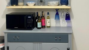Una cocina con microondas, botellas de vino y adornos en las repisas.