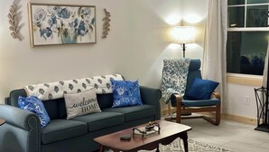 Una sala de estar con sofá, sillón, mesa de centro y lámpara.