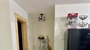 Un pasillo con una puerta de madera, un refrigerador negro y un paño estampado colgado en un perchero de madera.