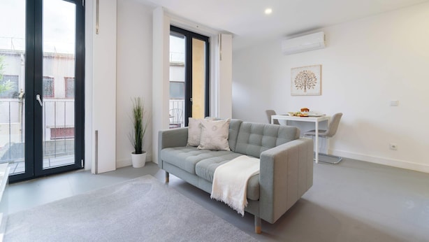 Ein modernes Wohnzimmer mit einem grauen Sofa, einem kleinen Tisch und einem Blumentopf.