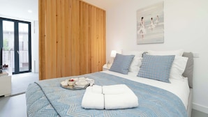 Ein modernes Schlafzimmer mit einem großen Bett, einer Wandpaneele aus Holz und einem Bild von Frauen an der Wand.
