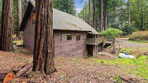 A cabin with a wooden exterior, a balcony, and a staircase leading to the entrance.