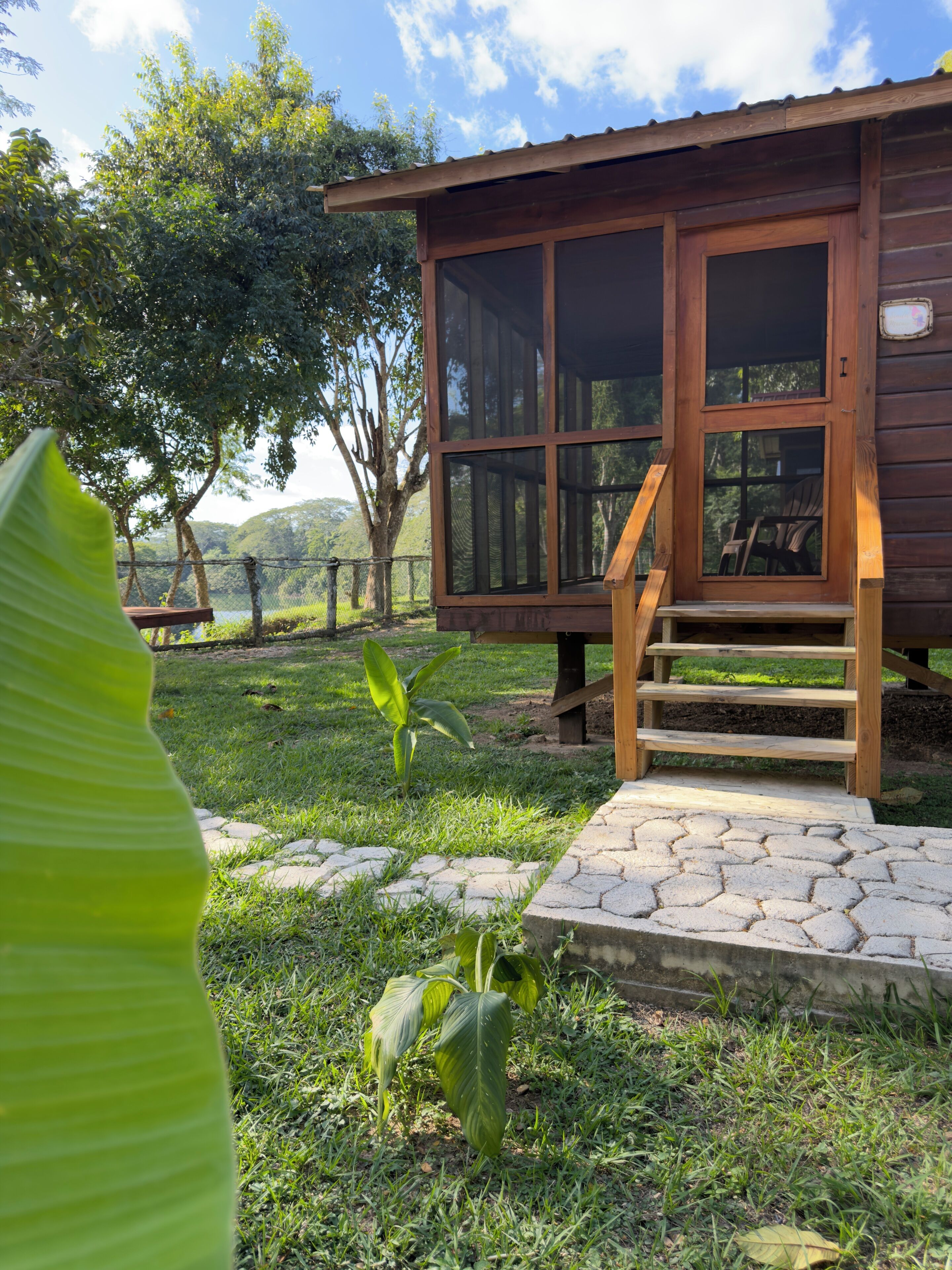 A wooden cabin with a porch and steps leading up to a door.
