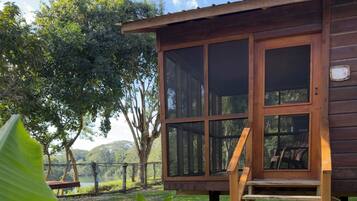 A wooden cabin with a porch and steps leading up to a door.