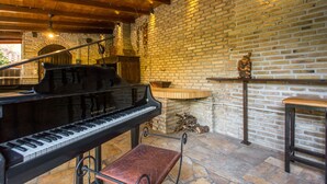 Un pianoforte a coda in una stanza accogliente con parete in mattoni, soffitto in legno e pavimento in pietra.