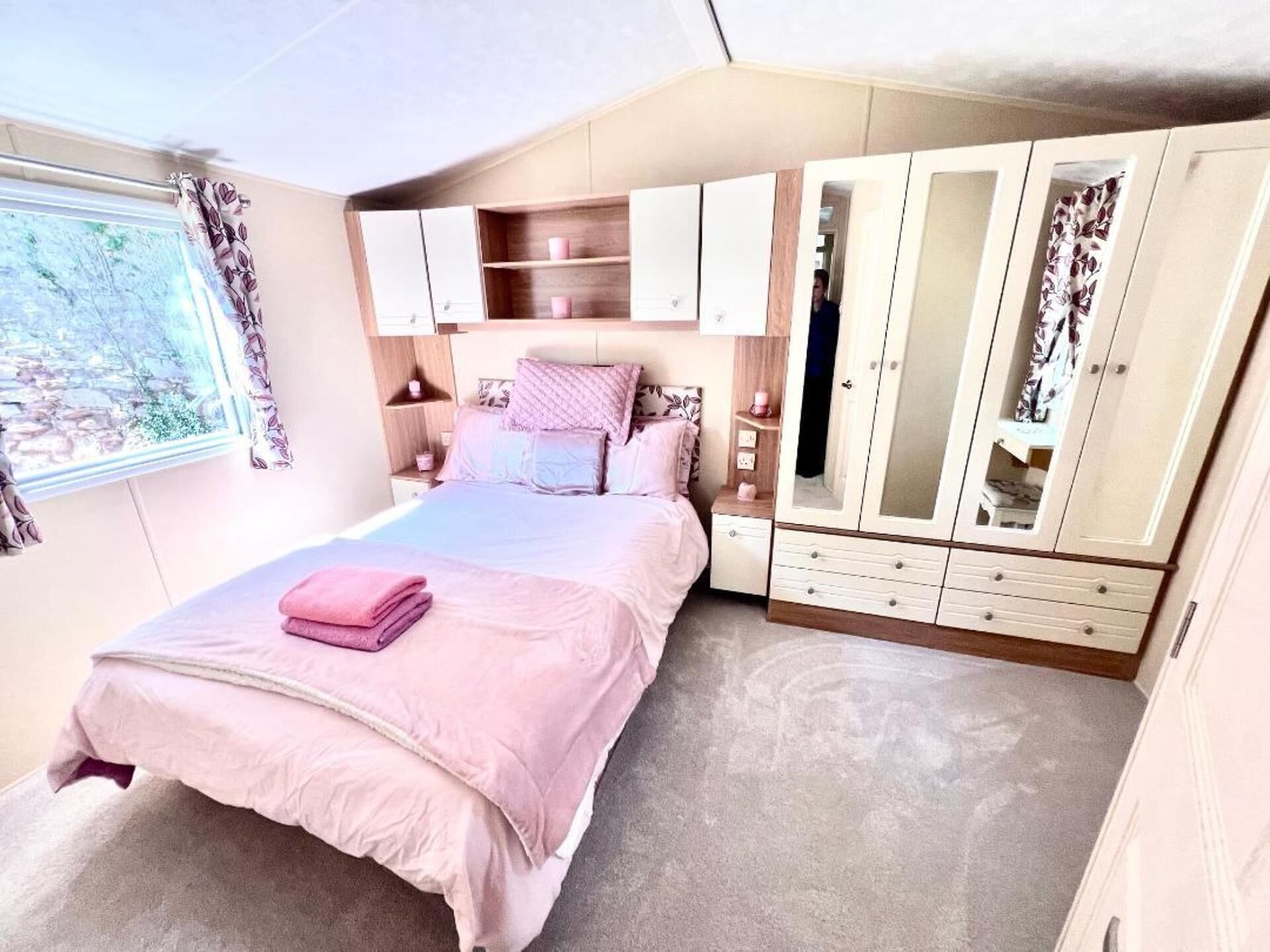 A bedroom with a bed, a wardrobe, and a window.