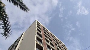 Un edificio alto con diversi piani e balconi, caratterizzato da un design architettonico moderno e colonne sagomate.