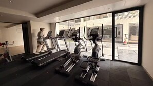 Una palestra con tapis roulant ed ellittiche, ampie finestre e una persona che corre.