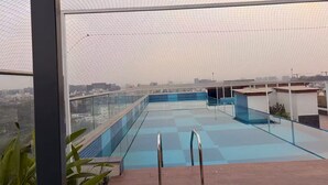 Una piscina sul tetto con ringhiere in vetro e scalette in metallo, circondata da una copertura a rete.