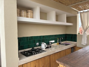 Una cocina con estufa a gas, hervidor y pileta.