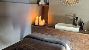 A spa room with a massage table, candles, a sink, and a decorative mirror. - Riad A l'Ombre du Palais (Marrakech)