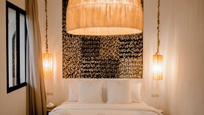 A bedroom with a large bed, a hanging light fixture, and a patterned wall. - Riad A l'Ombre du Palais (Marrakech)