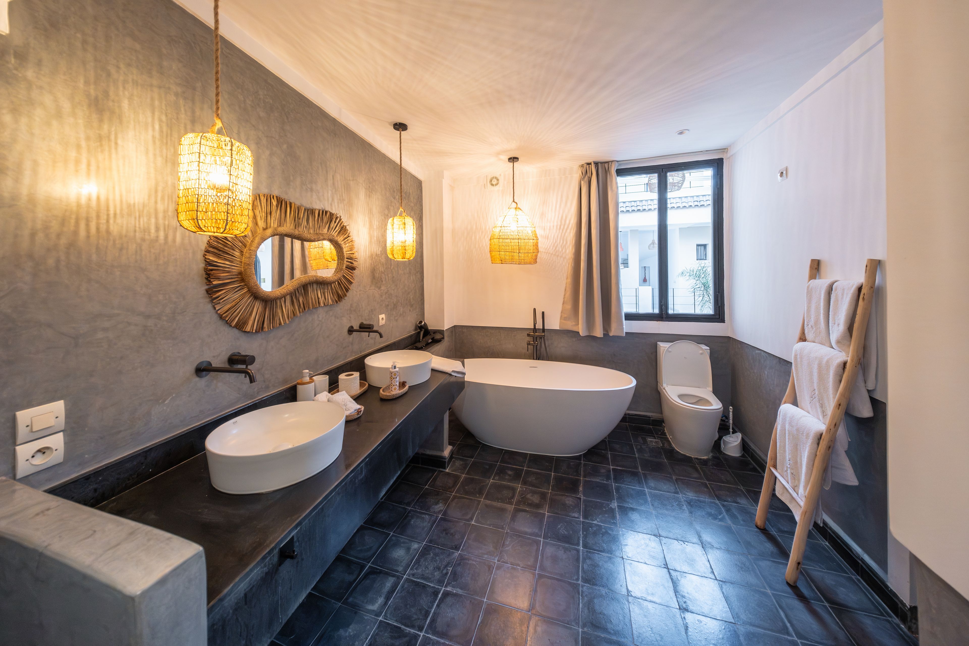 Un baño moderno con dos lavamanos, una bañera independiente y un espejo grande con marco decorativo.