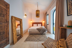 Habitación de hotel con una cama grande, un armario de madera, una lámpara colgante y vistas al exterior.