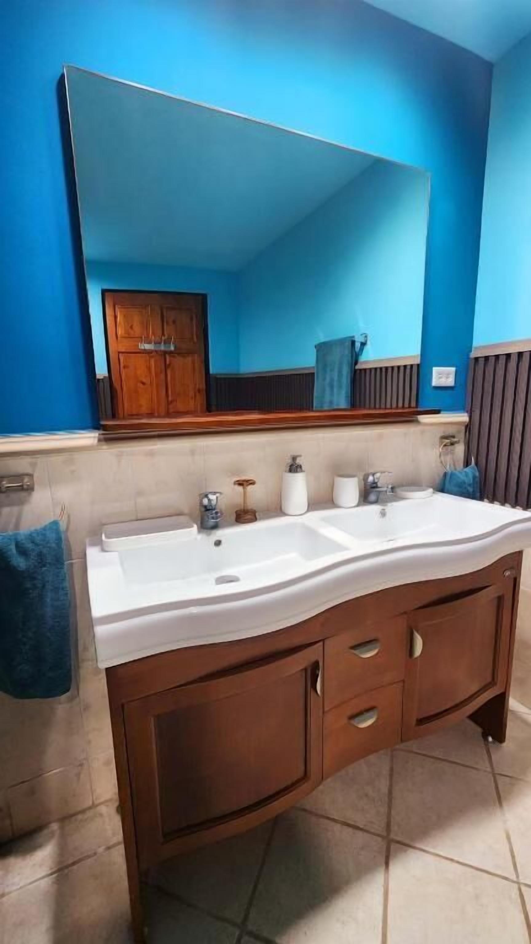 Un baño con lavamanos doble, muebles de madera y un espejo grande.