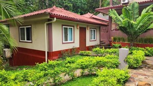 A small, single-story building with a red-tiled roof and a beige facade. It features a small porch area with a stone pathway leading to the entrance. - Coconut Lodge (Las Cumbres)