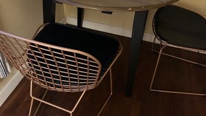 Een klein eetgedeelte met een ronde tafel en twee stoelen van draadstaal.