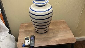 Een nachtkastje met een lamp, een telefoon en een afstandsbediening.
