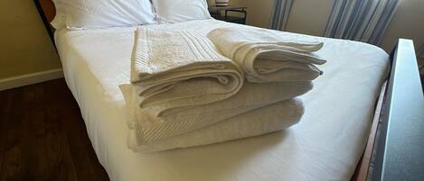 Un lit bien fait, avec du linge de lit blanc et des serviettes pliées.