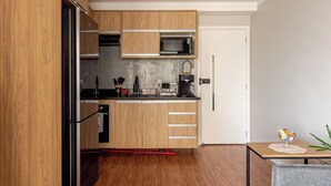 A modern kitchen with wooden cabinets, a microwave, and a coffee machine.
