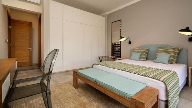 A bedroom with a bed, a chair, a bedside table, a lamp, and a wardrobe. - Luxurious & peaceful blend villa in Royal Park Balaclava Mauritius 2 (Balaclava)