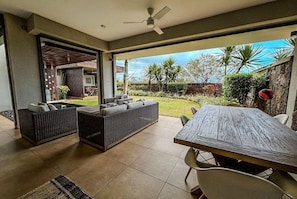 Un espace de vie à aire ouverte comprenant une table à manger, deux canapés et un ventilateur de plafond.