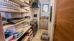 Un lavadero con estantes llenos de ropa doblada, una lavadora y una secadora.