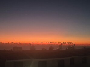 Ein Sonnenuntergang über einer Stadtlandschaft, Gebäude silhouettiert am Himmel.