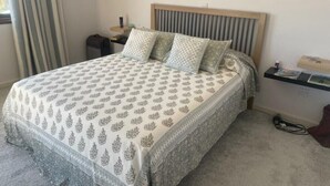 A neatly made bed with patterned bedding, a wooden headboard, and two wall-mounted lamps. - A family orientated  home to make memories, on the sun soaked island of Cyprus (Tala)