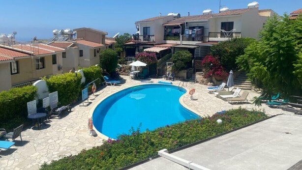 A swimming pool surrounded by lounge chairs and a building with balconies. - A family orientated  home to make memories, on the sun soaked island of Cyprus (Tala)