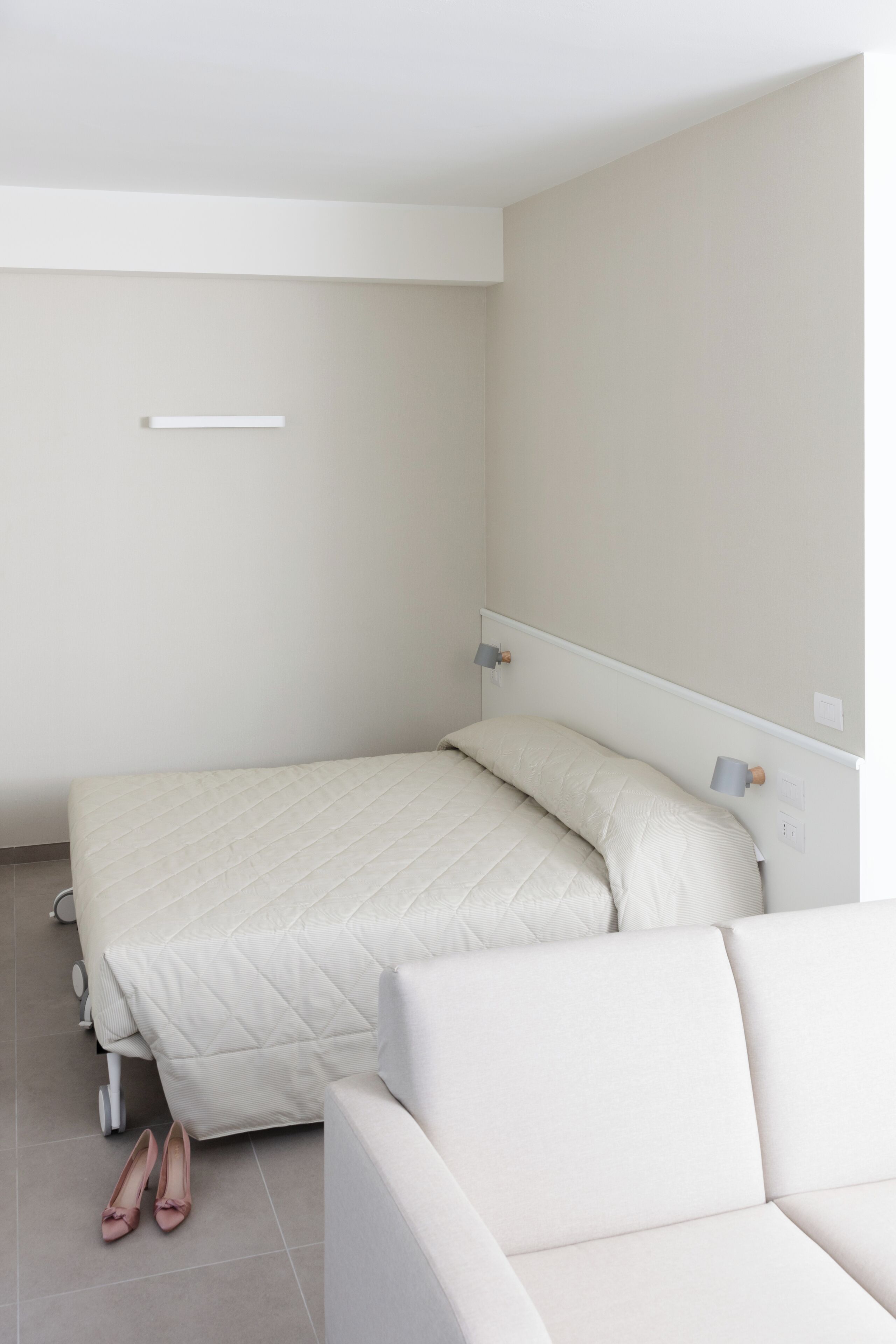 A minimalist bedroom with a bed, a nightstand, and a small table.